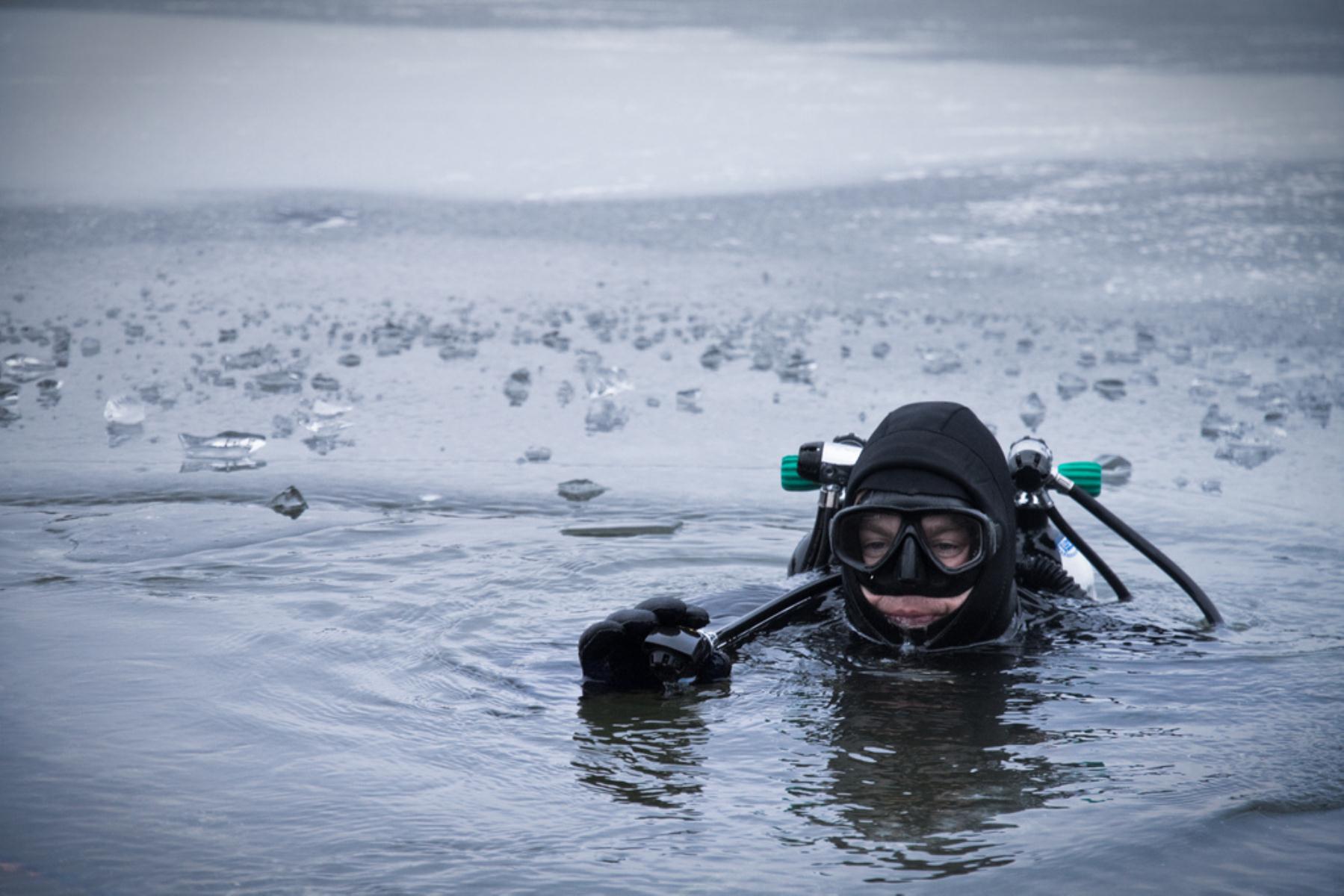 Diver preparing to drop beneath the surface in an icy lake
