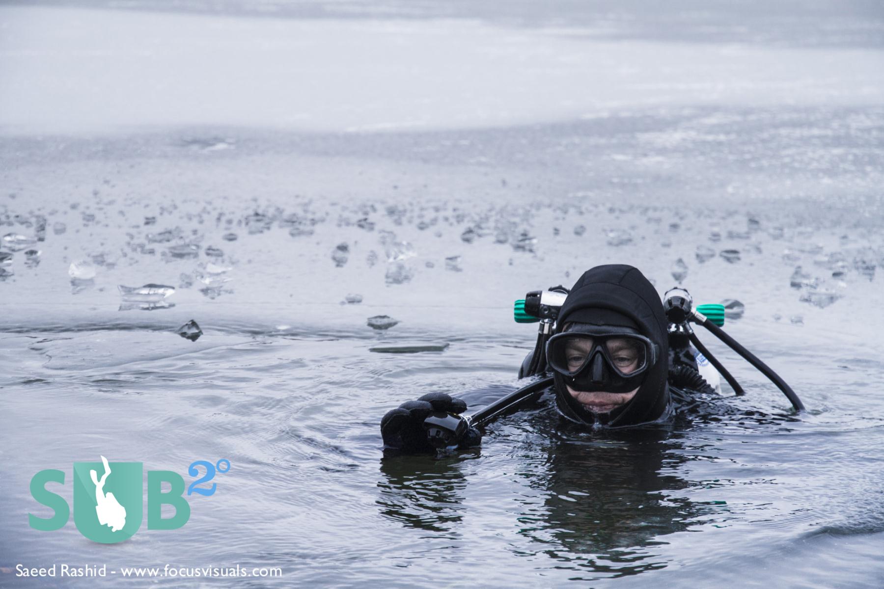 Diver preparing to drop beneath the surface in an icy lake 