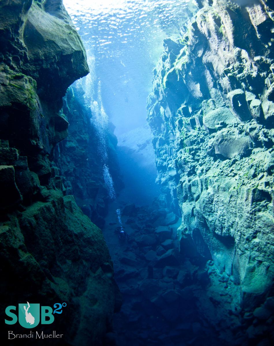 A diver diving in-between the North American and European continental plates at Silfra Crack, Iceland.
